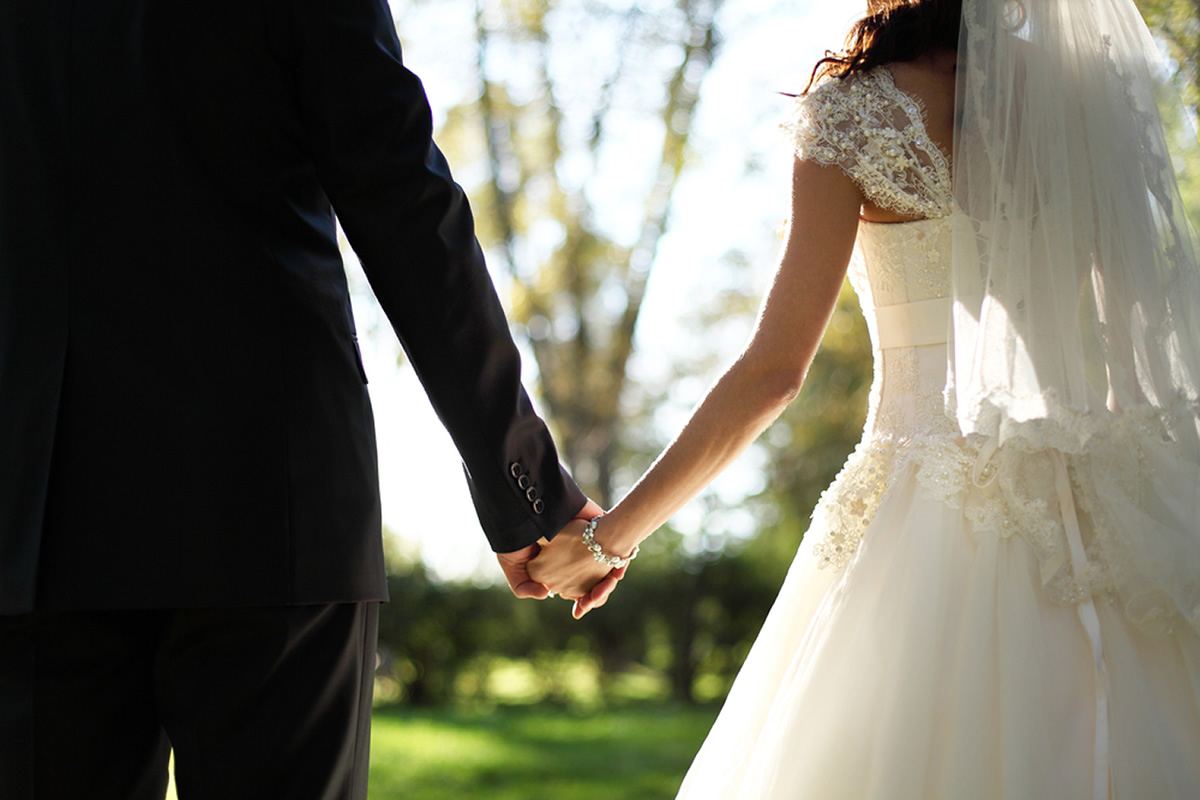 Novios tomados de la mano en una ceremonia al aire libre